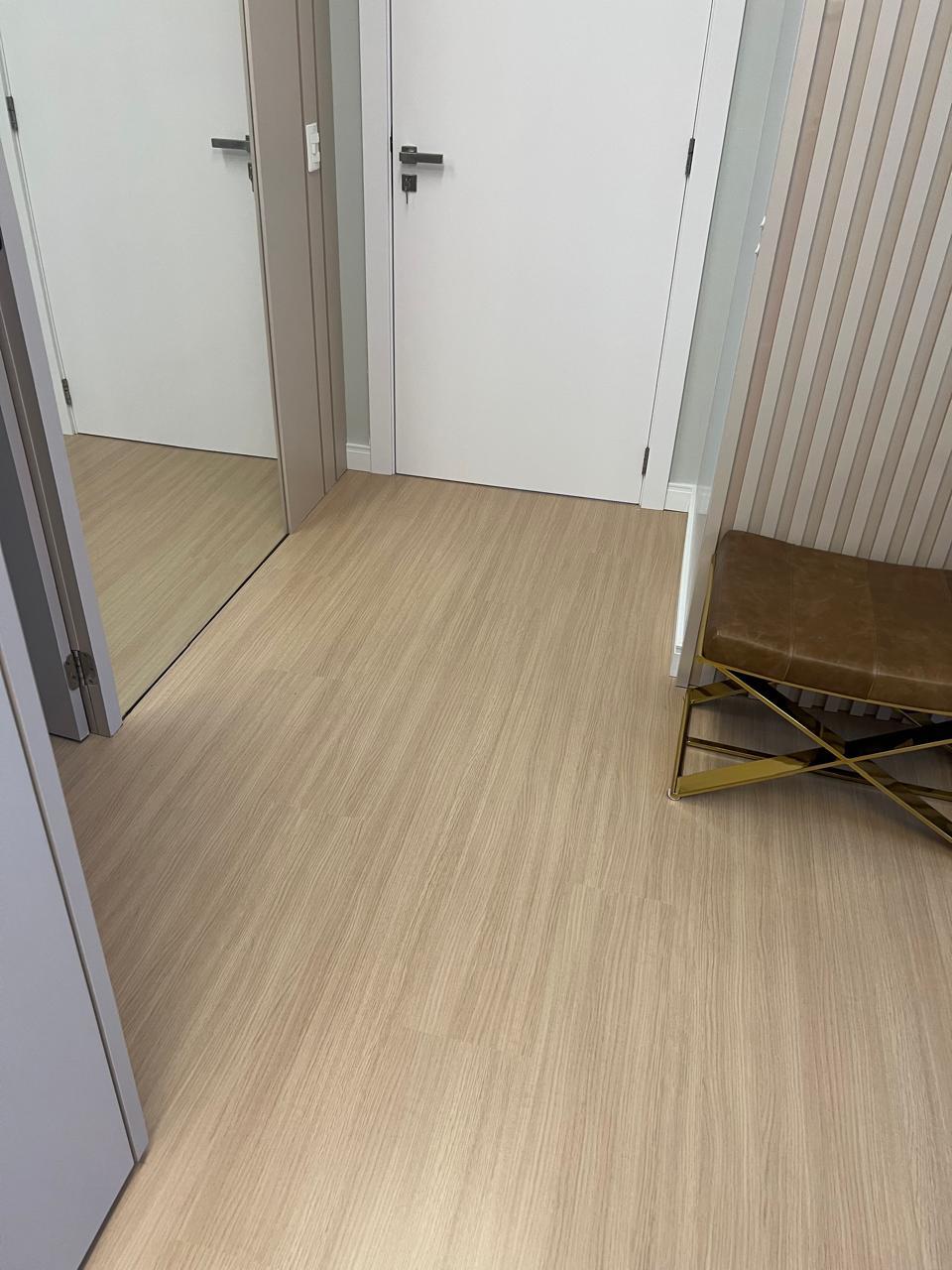 Piso vinílico claro em hall com portas brancas