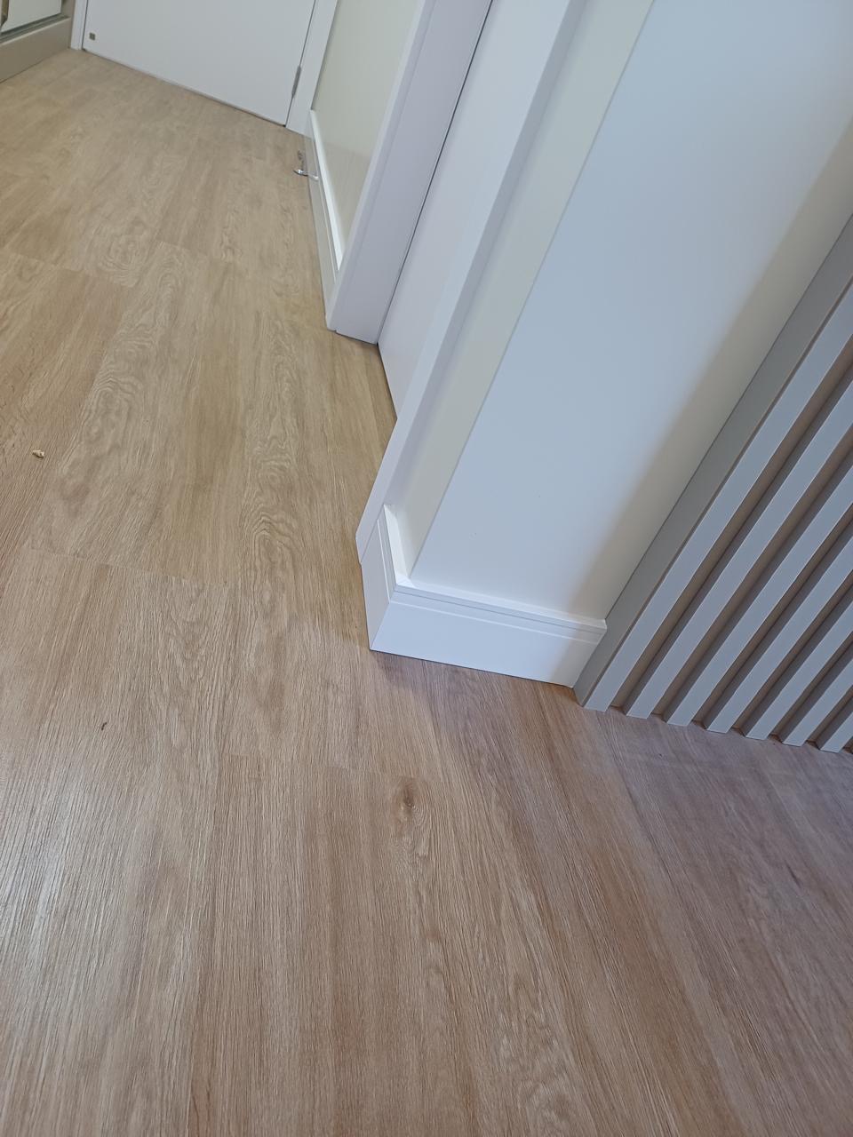 Piso vinílico com rodapé branco e acabamento em ripado