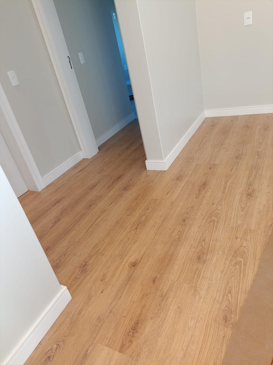 Piso laminado em sala com rodapé branco